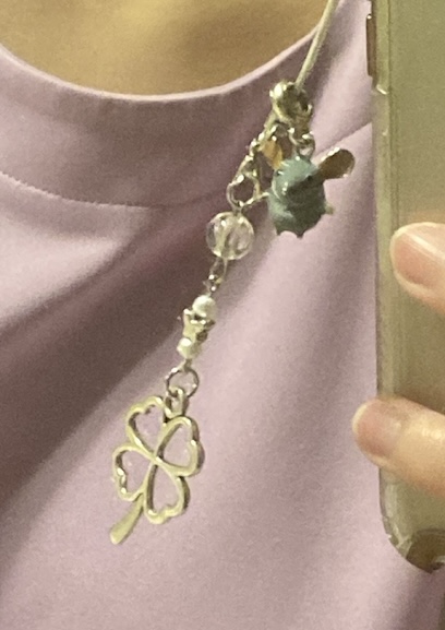 photo of a phone charm with a four-leaf clover and a mouse charm.